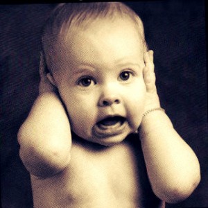 Bebê tapando seus ouvidos.